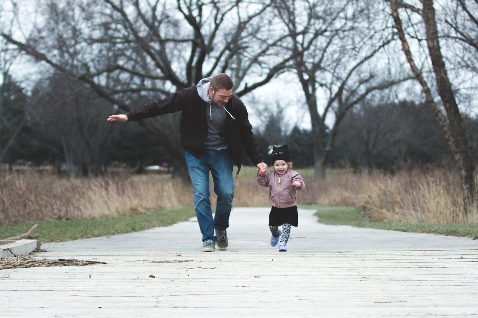 man and girl running on asphalt road